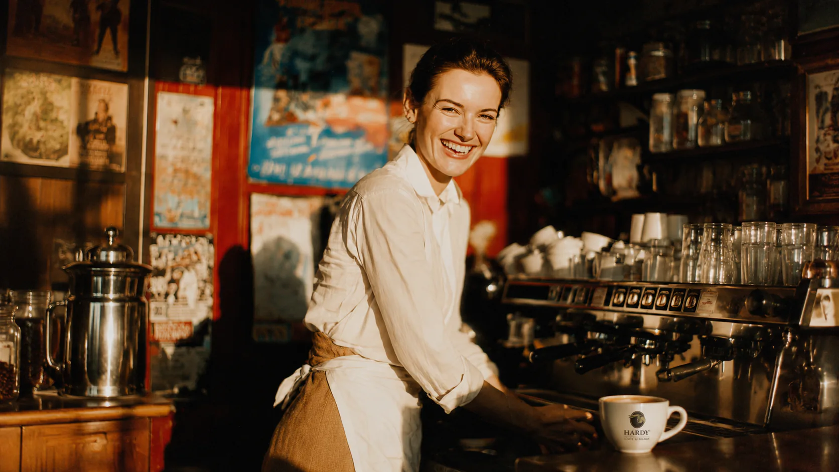 Hardy barista at the counter with a Hardy cup — professional service